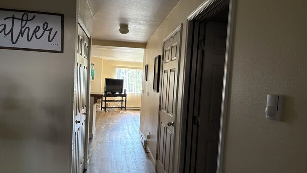 A hallway with a sign on the left, a door on the right, and a television in the background. - Bigfork Harbor Retreat (Bigfork)