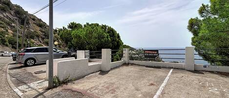 A parking area with a concrete barrier, a sign for 'VENDIDO INTERIM', and a view of the sea.