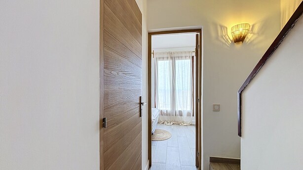 A hallway with a wooden door, a staircase, and a bed with a white canopy. - BRAMER 36 Rosas / Roses - INTERimmo (Rosas / Roses)
