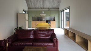 A modern living room with a leather sofa, a wooden coffee table, and a kitchen in the background.