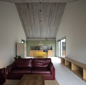 A modern living room with a leather sofa, a wooden coffee table, and a kitchen in the background.