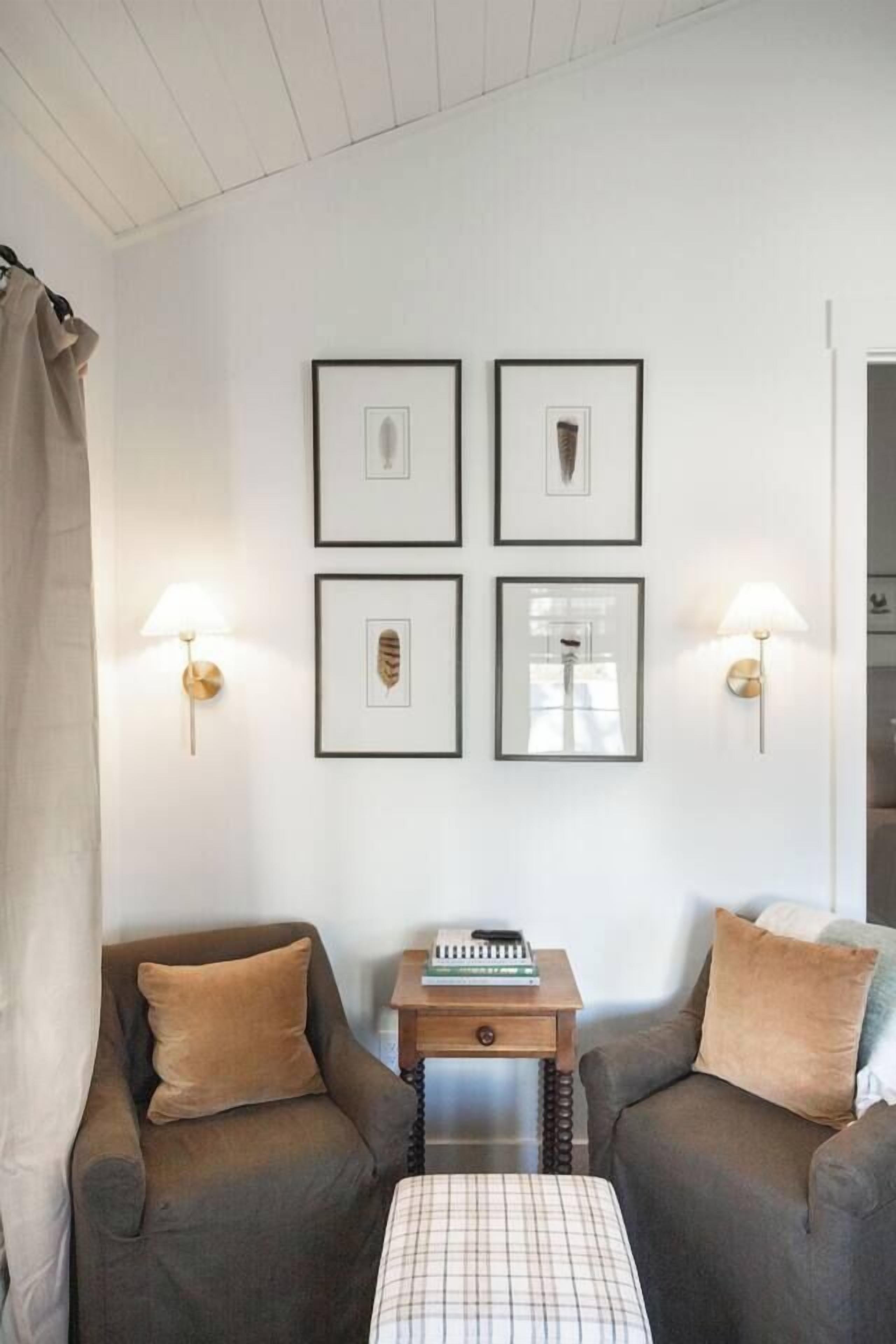 A room with two sofas, a small table with a book, and framed pictures on the wall.