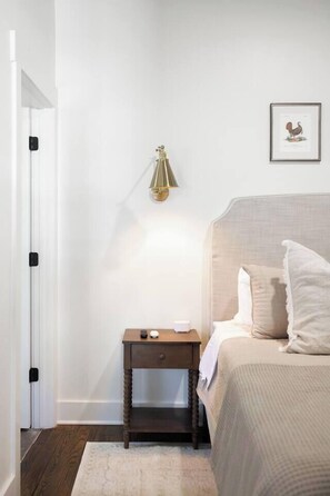 Ein Schlafzimmer mit Bett, Nachttisch, Lampe und einem gerahmten Bild an der Wand.