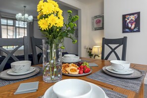 Taula de menjador amb un ram de flors grogues, plats de menjar i tasses.
