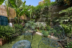 A garden with two metal chairs, a wooden fence, and various plants. - Eclectic Character Home | Garden & City Location - Pass the Keys (Brighton)