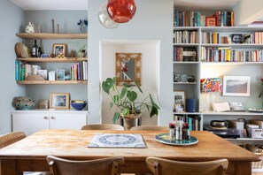 Un espace repas comprenant une table en bois, des chaises et une plante en pot placée au centre.