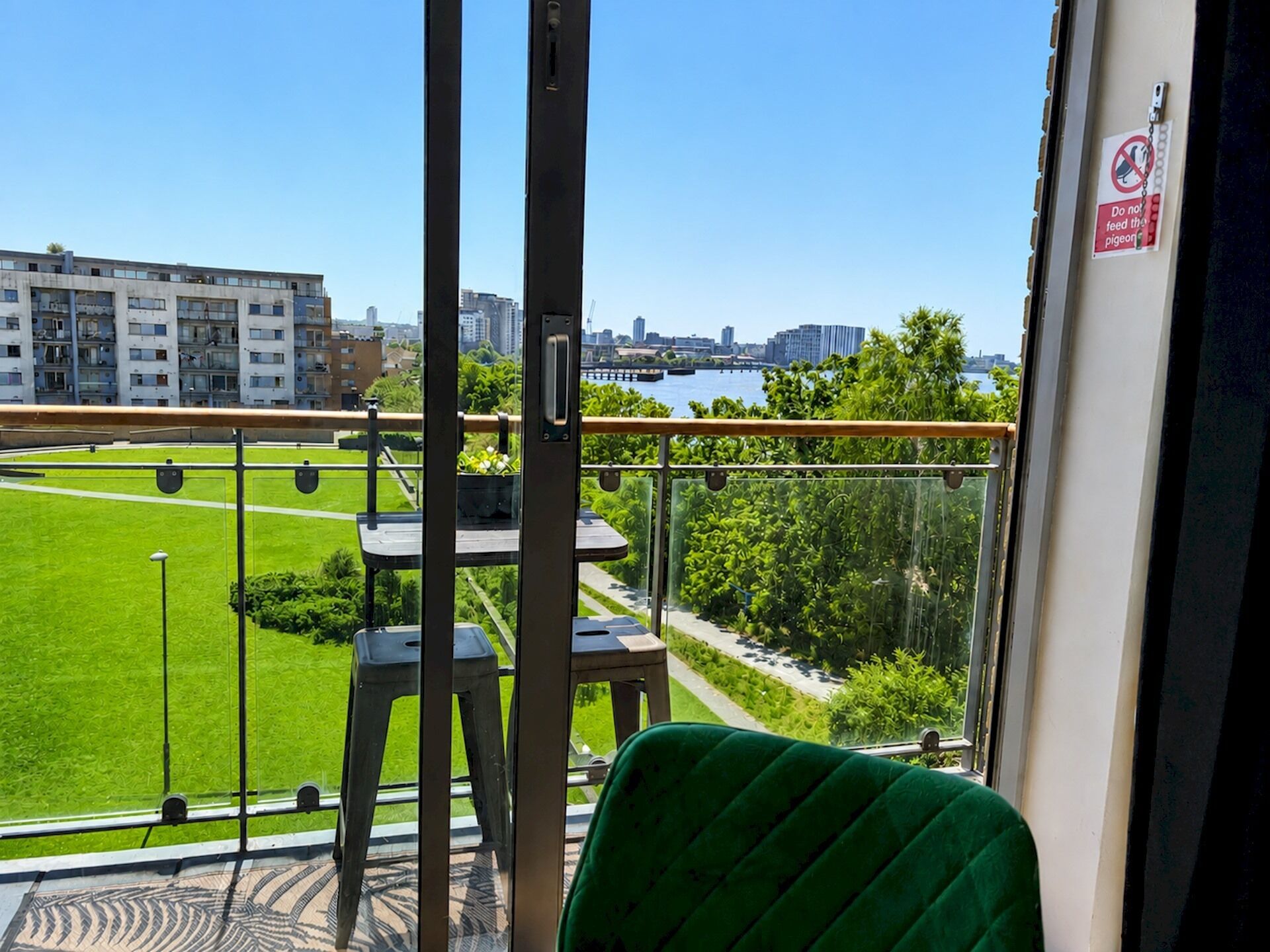 Un balcó amb vista a un camp verd, una taula i cadires.