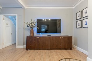 Ein Wohnzimmer mit einer Holzunterhaltungsecke, einem Flachbildfernseher und einer Vase mit Blumen.