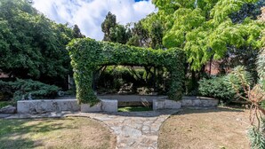 A garden with a stone pathway, a covered seating area, and various plants. - Luxury 4-Bedroom house near Southend - Pass the Keys (Southend-on-Sea)