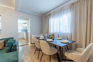 A dining area with a table set for four, a sofa, and a kitchen in the background. - Luxury 4-Bedroom house near Southend - Pass the Keys (Southend-on-Sea)