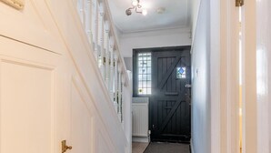 A hallway with a wooden floor, white walls, and a black door at the end. - Luxury 4-Bedroom house near Southend - Pass the Keys (Southend-on-Sea)