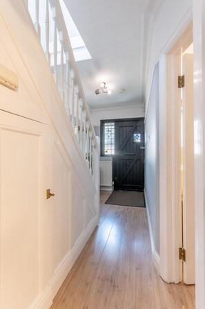 A hallway with a wooden floor, white walls, and a black door at the end. - Luxury 4-Bedroom house near Southend - Pass the Keys (Southend-on-Sea)