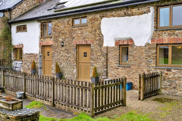 A stone house with a white exterior, wooden doors, and a wooden fence. - Inviting Holiday Cottage in Beaworthy (Beaworthy)