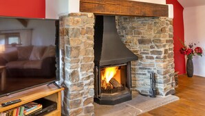 A stone fireplace with a TV on a stand in front of it. - Inviting Holiday Cottage in Beaworthy (Beaworthy)