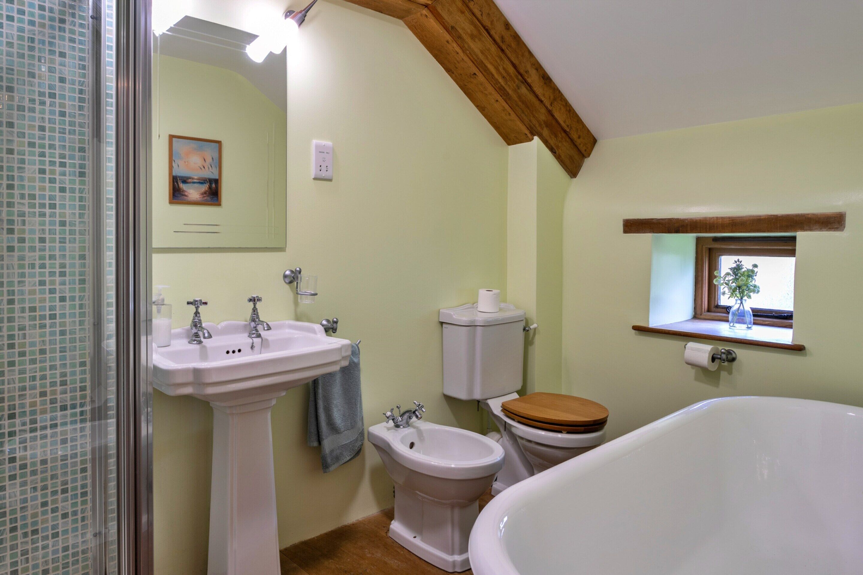 A bathroom with a sink, bidet, toilet, and bathtub.
