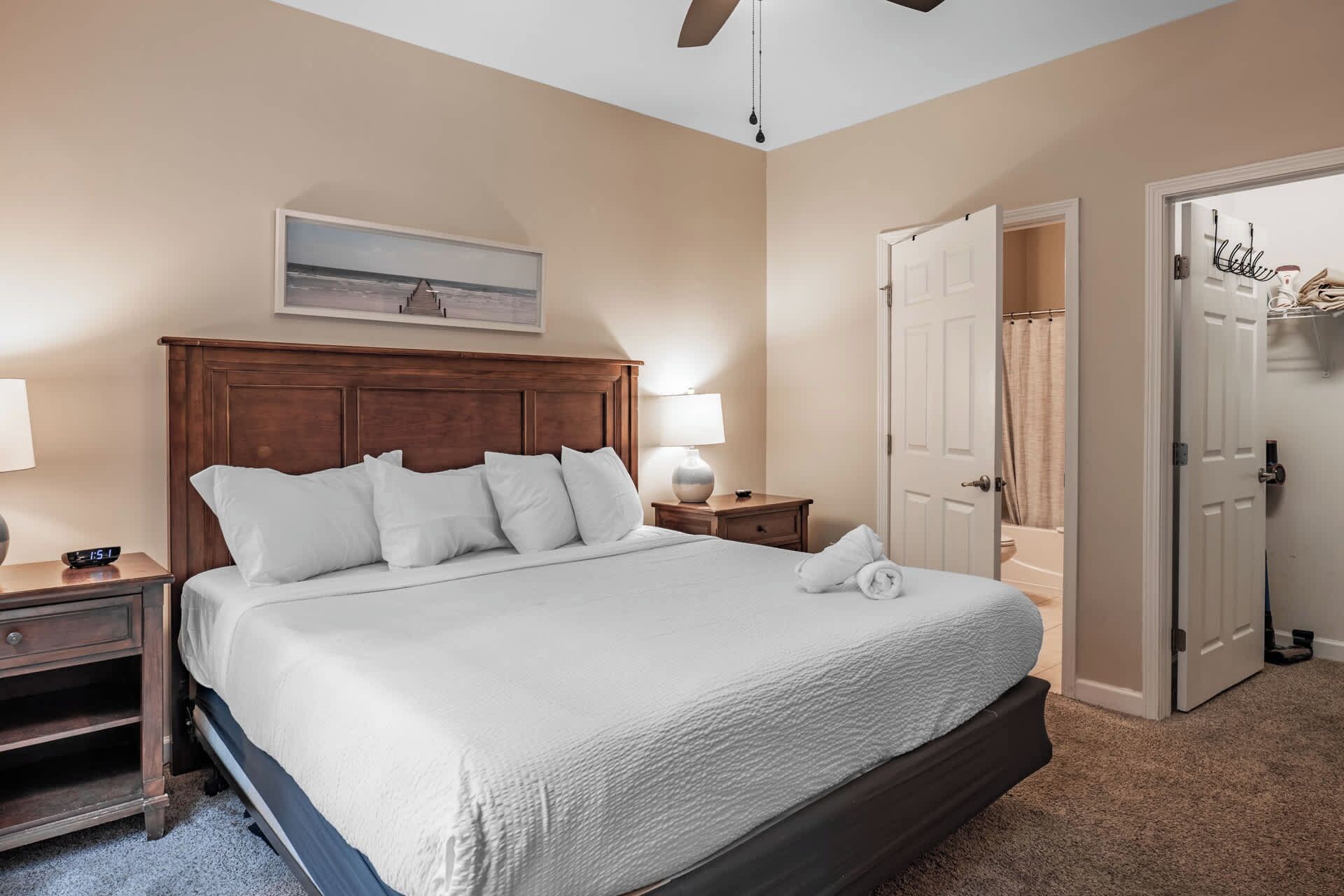 Une chambre à coucher avec un grand lit, une table de chevet, une lampe, un tableau et une porte donnant sur une salle de bain.