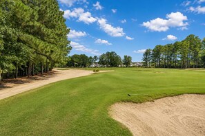A golf course with a clear sky, sand bunkers, and trees. - Willow Bend At Barefoot 1111 (North Myrtle Beach)