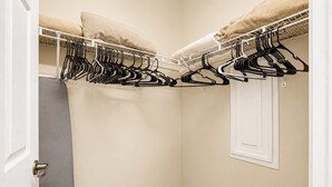 Ein begehbarer Kleiderschrank mit weißer Tür, beige Wänden und einem weißen Boden.