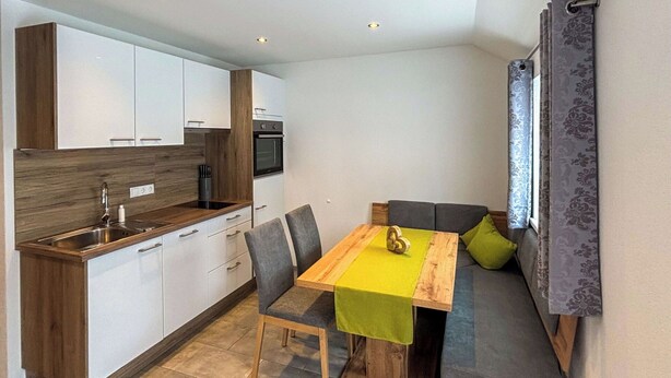 Eine kleine Küche mit weißen Schränken, einer Holz Arbeitsplatte und einem eingebauten Backofen.