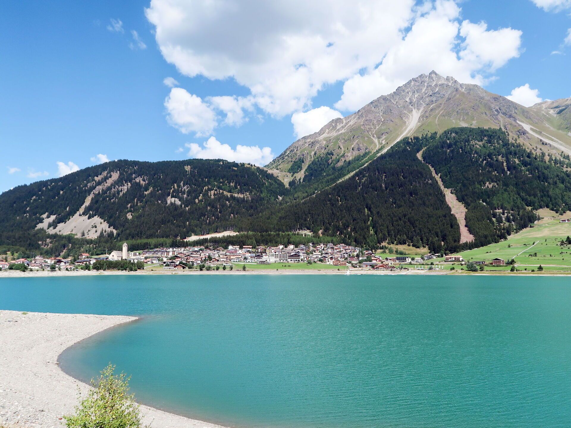 Eine Stadt am See mit Bergblick, mit einer markanten Kirche und blauem Himmel.