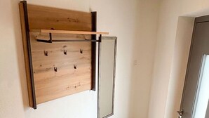 Ein modernes Interieur mit einem Holz-Kleiderständer, einer Bank und einer Tür.