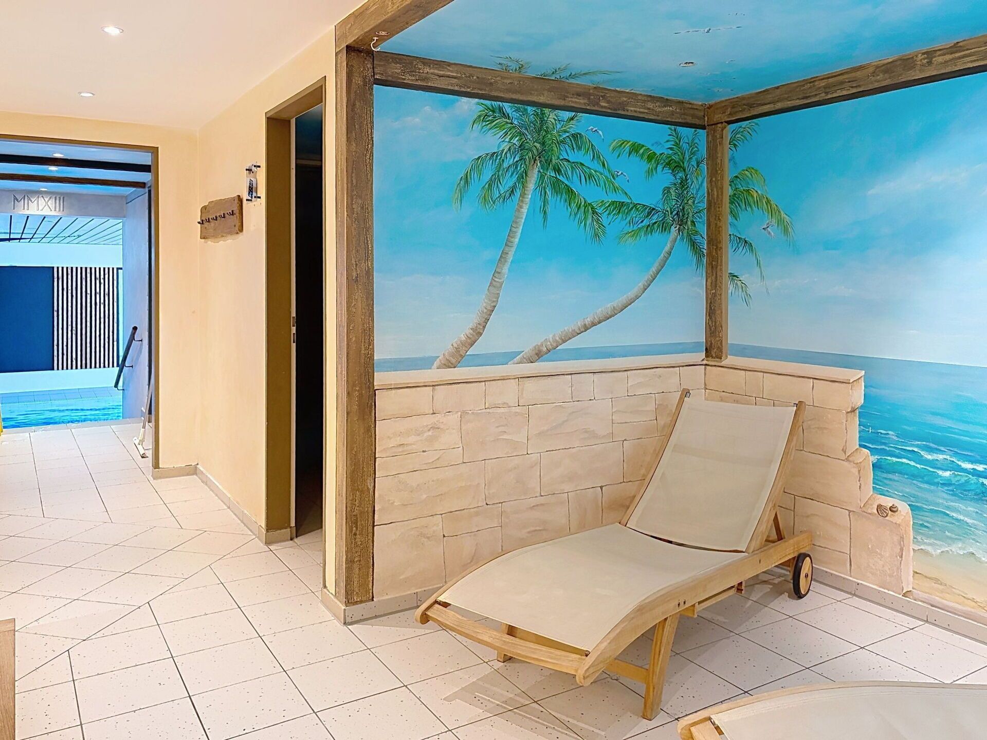 Una habitació amb un mural de platja, una cadira de relax i vista a l'oceà.