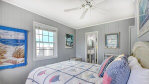 A bedroom with a bed, a ceiling fan, a window, and artwork on the walls. - Sail Away - 4 Bedroom, 2.5 Bath Beach Home - Dog Friendly with Fenced In Yard (Garden City Beach)