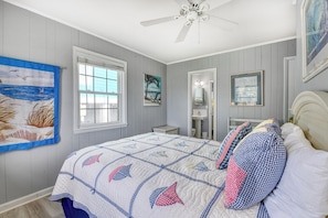 A bedroom with a bed, a ceiling fan, a window, and artwork on the walls. - Sail Away - 4 Bedroom, 2.5 Bath Beach Home - Dog Friendly with Fenced In Yard (Garden City Beach)