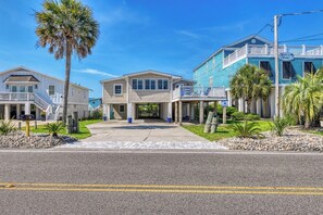 A beachfront property with a covered driveway, a two-story building, and a blue house with a balcony. - Sail Away - 4 Bedroom, 2.5 Bath Beach Home - Dog Friendly with Fenced In Yard (Garden City Beach)