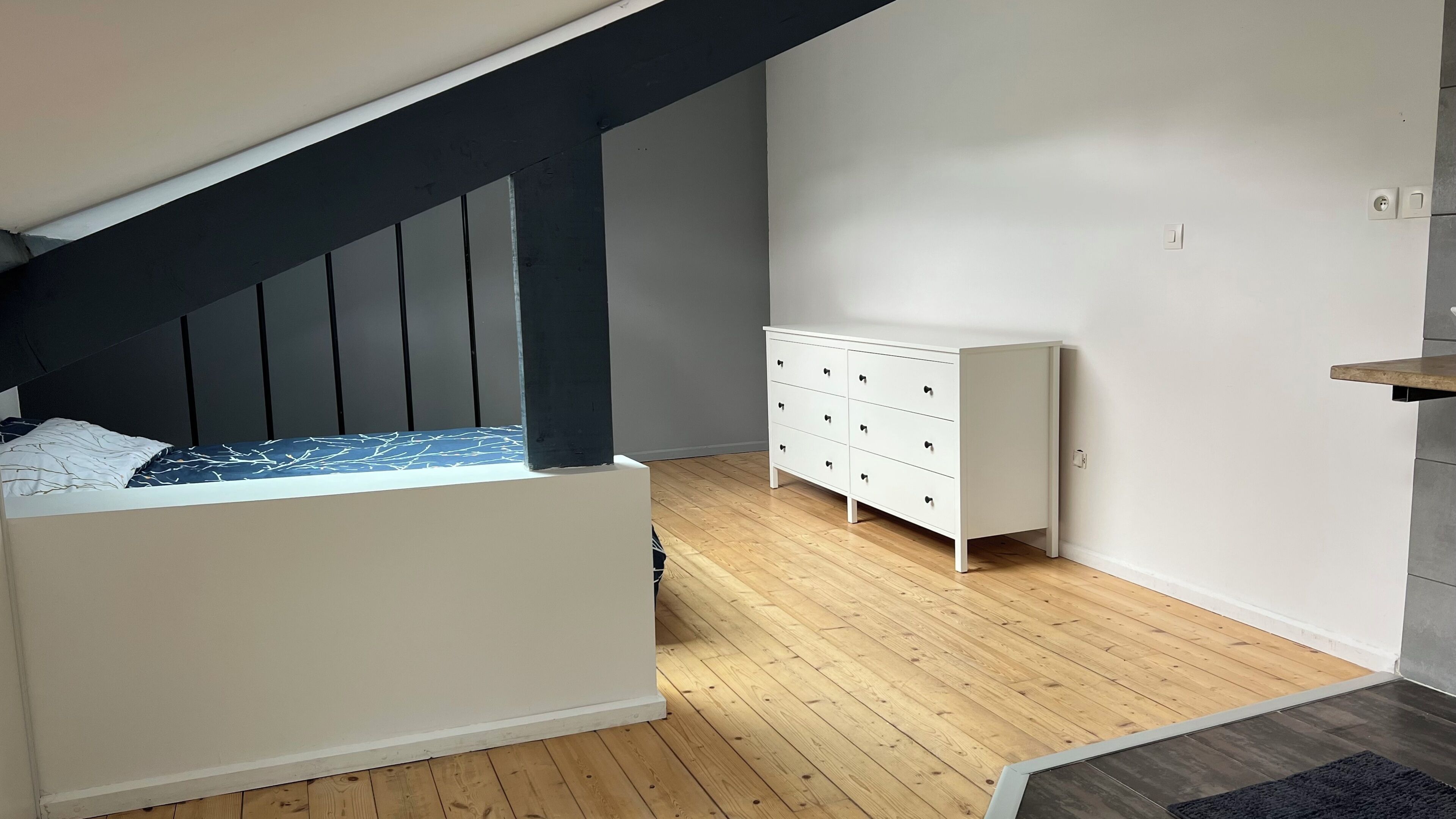 Un dormitorio con cama, cómoda y techo inclinado.