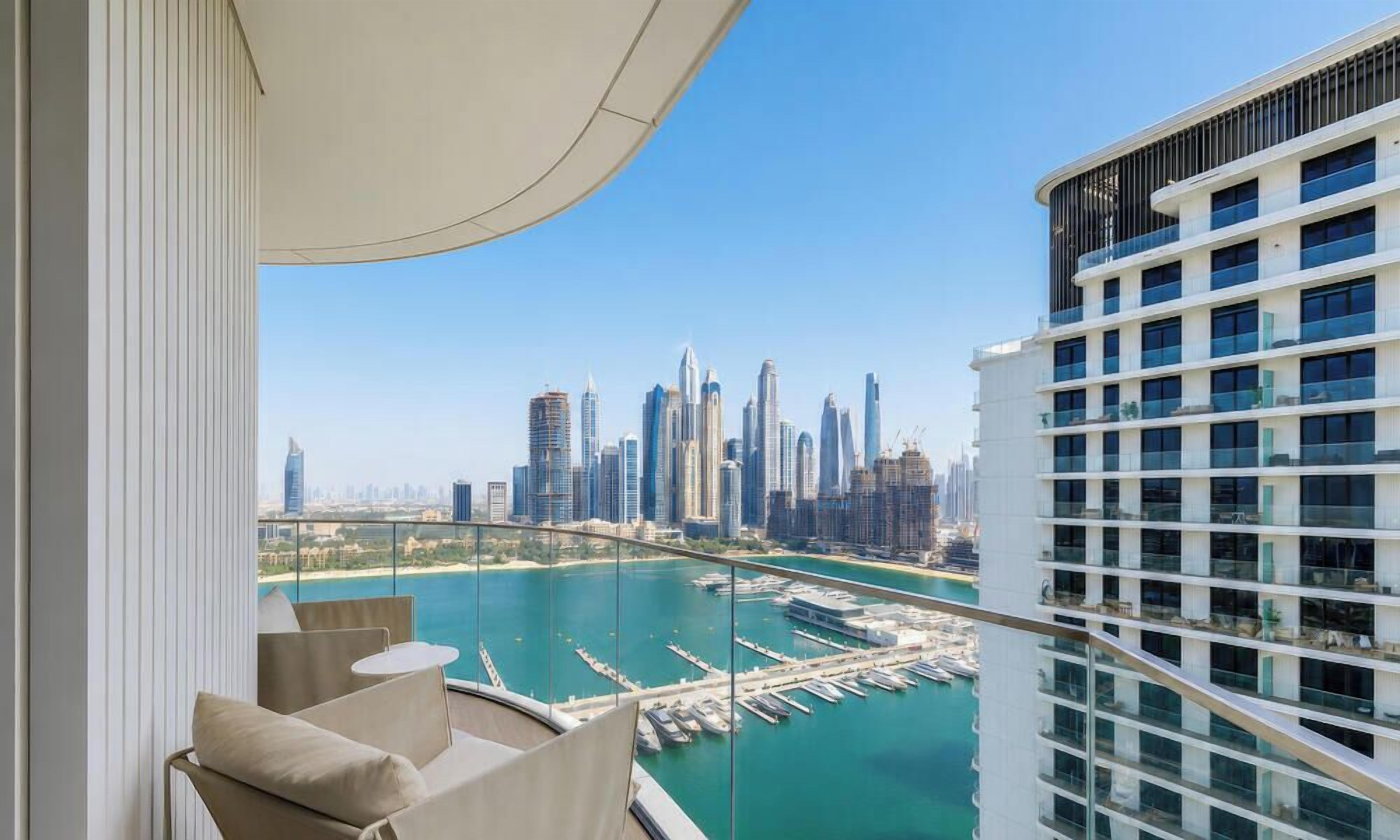 A balcony with a view of a marina and a city skyline.