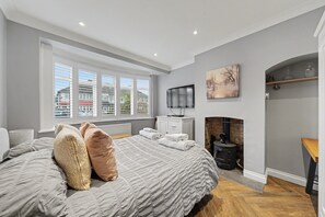 Quarto com uma cama grande, lareira, televisão e janela com persianas.
