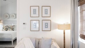 Ein Zimmer mit einem Bett, einer Couch, einer Lampe und gerahmten Bildern an der Wand.