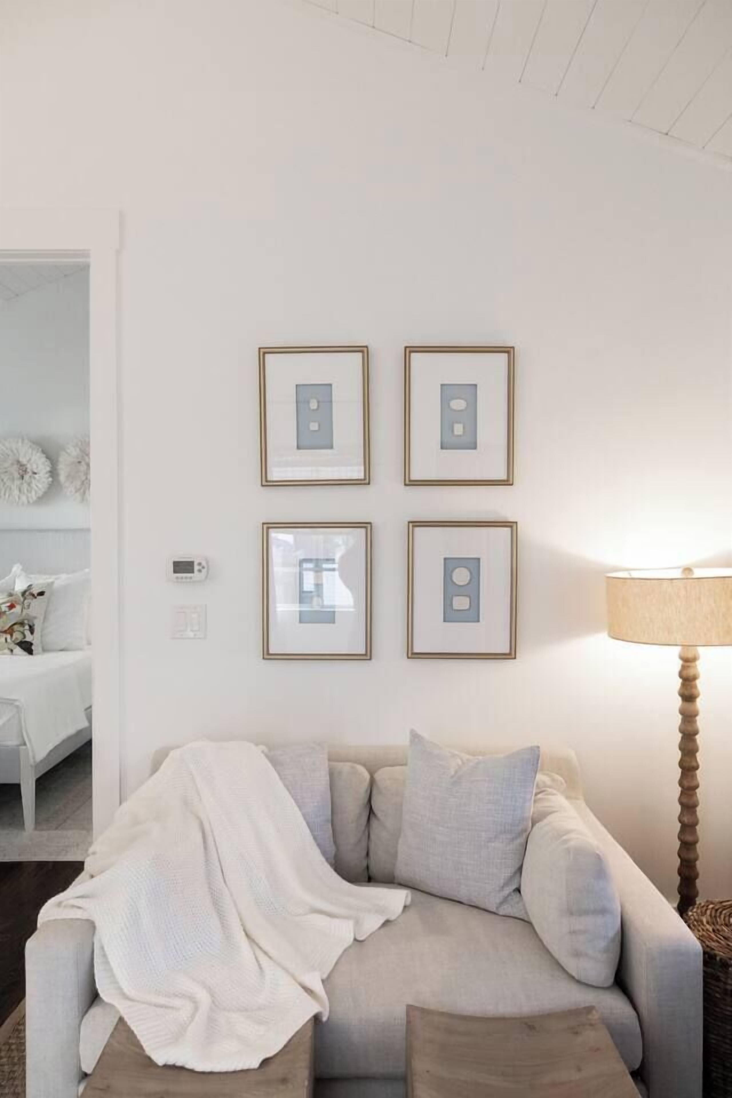 A living room with a sofa, a lamp, and framed pictures on the wall.