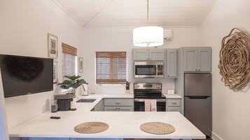A compact kitchen with a central island, a microwave, oven, and refrigerator.