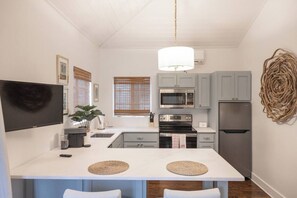 Una cocina compacta con una isla central, microondas, horno y refrigerador.