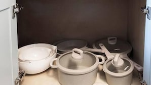 Ein Küchenschrank mit einer Schublade und einem Einlegeboden mit Töpfen und Pfannen.