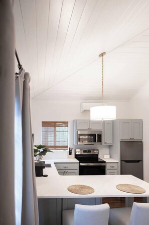 A modern kitchen with a central island, stainless steel appliances, and light grey cabinetry.