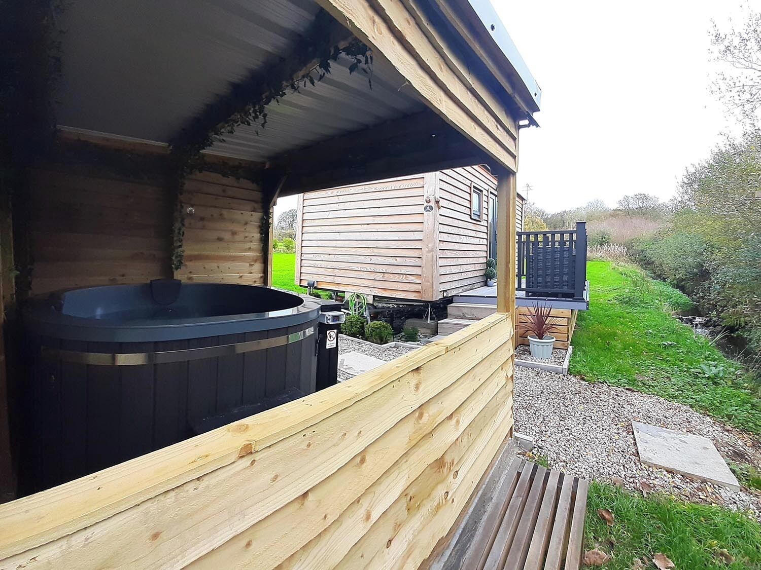A wooden cabin with a hot tub and a small deck area.