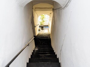 Eine enge Treppe führt zu einer höheren Ebene, mit einem Geländer auf einer Seite und einer Pflanze oben.