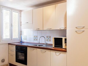 A kitchen with white cabinets, a sink, a stove, and a microwave. - Lovely apartment for 3 people with A/C (Imperia)