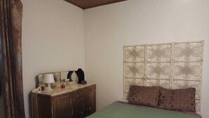 A bedroom with a bed, a dresser, a lamp, and a decorative headboard. - Green Palace-Guest House (Vale de Figueira)