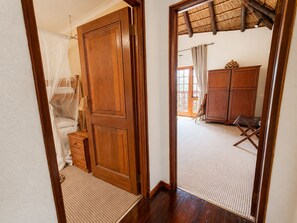 A wooden door leading to a room with a bed, a wardrobe, and a window with curtains. - Jembisa Bush Home - All Inclusive (Melkrivier, Waterberg)