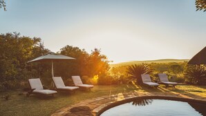 A pool area with lounge chairs and a canopy, surrounded by greenery. - Jembisa Bush Home - All Inclusive (Melkrivier, Waterberg)