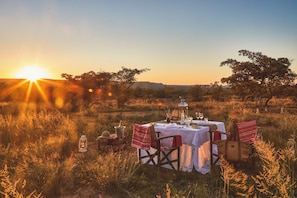 Una mesa montada en un campo cubierto de hierba, con un atardecer de fondo.