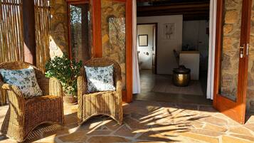 A stone-floored room with wicker furniture and a doorway leading to a bathroom.