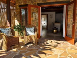 A stone-floored room with wicker furniture and a doorway leading to a bathroom.
