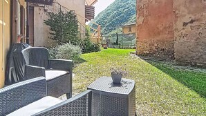 Um pátio com mesas ao ar livre, uma pequena mesa com uma planta e uma montanha ao fundo.