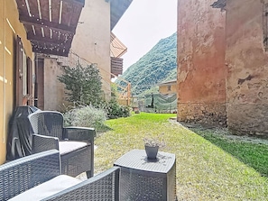 Ein Innenhof mit Außenplätzen, ein kleiner Tisch mit Pflanze und ein Berg im Hintergrund.