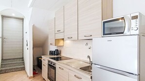 Uma cozinha compacta com micro-ondas, forno e pia.